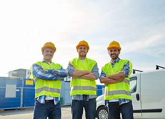 Image showing happy male builders in high visible vests outdoors