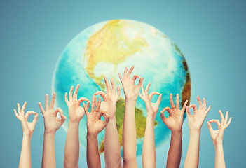 Image showing human hands showing ok sign over earth globe