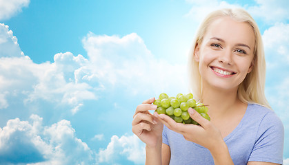Image showing happy woman eating grapes over sky