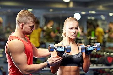 Image showing young couple with dumbbells flexing muscles in gym