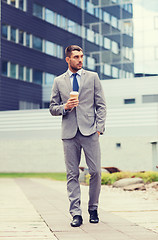 Image showing young serious businessman with paper cup outdoors