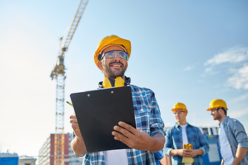 Image showing builder in hardhat with clipboard at construction