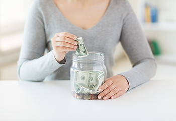 Image showing close up of woman hands and dollar money in jar