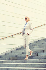 Image showing young smiling businesswoman walking down stairs