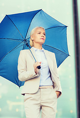 Image showing young serious businesswoman with umbrella outdoors