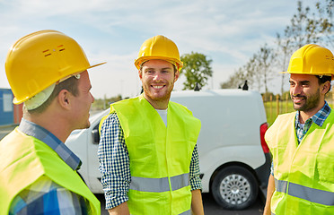 Image showing happy male builders in high visible vests outdoors