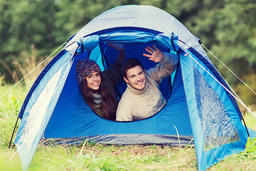 Image showing smiling couple of tourists looking out from tent