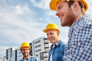 Image showing group of smiling builders in hardhats outdoors