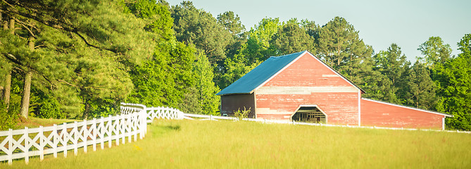 Image showing  white fence leading up to a big red barn