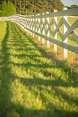 Image showing  white fence leading up to a big red barn