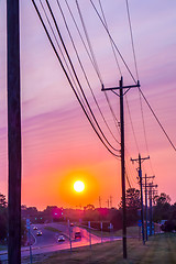 Image showing silhouetted electric pylon with power line at sunset