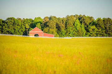 Image showing  white fence leading up to a big red barn