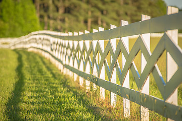 Image showing  white fence leading up to a big red barn