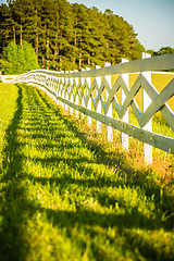 Image showing  white fence leading up to a big red barn