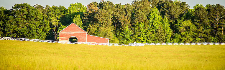 Image showing  white fence leading up to a big red barn