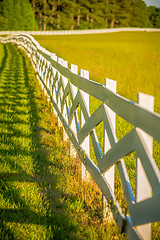 Image showing  white fence leading up to a big red barn