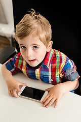 Image showing Little boy plays with smartphone 