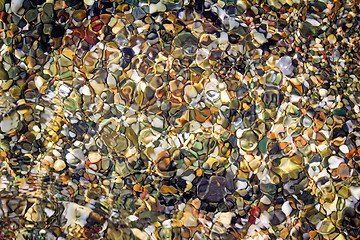 Image showing Small sea stones on the seashore, covered with a sea wave.