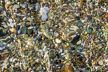 Image showing Small sea stones on the seashore, covered with a sea wave.