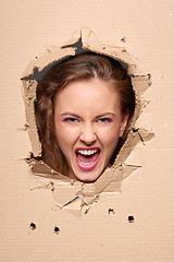 Image showing Screaming girl peeping through hole in paper