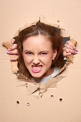 Image showing Angry girl peeping through hole in paper