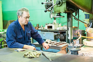 Image showing Senior worker operates metalworking machine