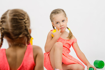 Image showing Girl misunderstanding looks at her sister while playing with toys