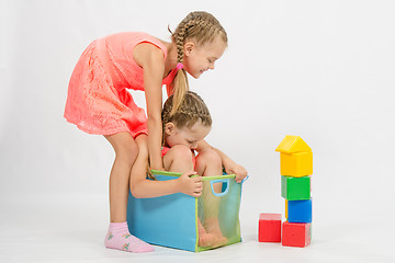 Image showing Girl tries to pull another girl out of the box