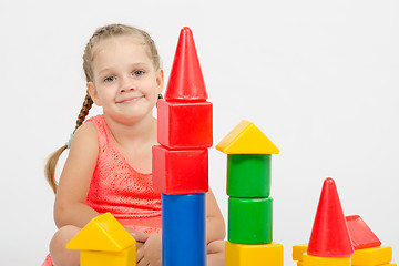 Image showing The four-year girl sits at a house out of blocks