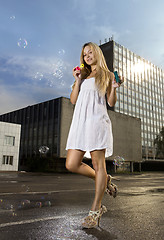 Image showing woman blowing soap bubbles on street 