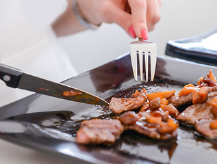 Image showing dish of pork with sauce on black plate