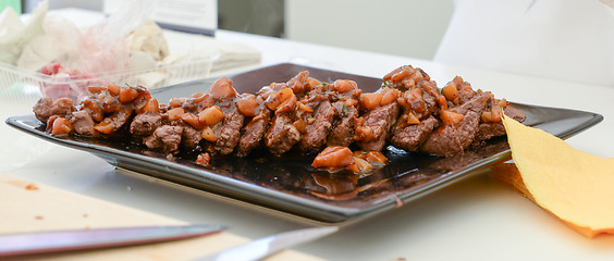 Image showing dish of pork with sauce on black plate