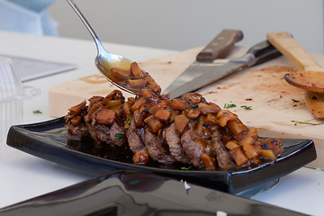 Image showing dish of pork with sauce on black plate