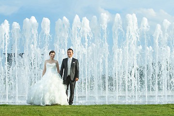 Image showing Bride and groom in front of water spray fountain