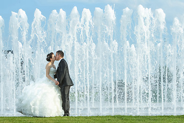 Image showing Bride and groom kissing in front of water fountain