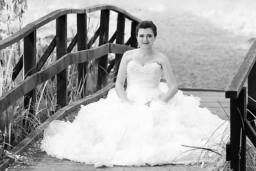 Image showing Bride sitting on wooden bridge black and white