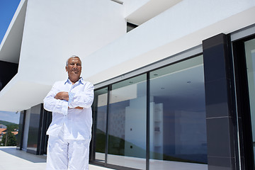 Image showing senior man in front of modern home