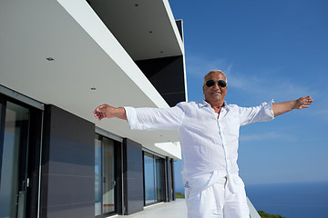 Image showing senior man in front of modern home