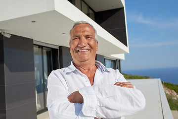 Image showing senior man in front of modern home