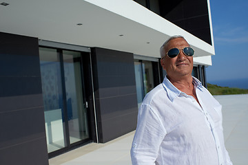 Image showing senior man in front of modern home