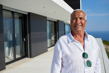 Image showing senior man in front of modern home