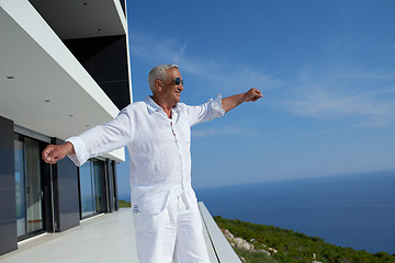 Image showing senior man in front of modern home