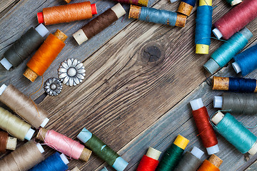 Image showing two old buttons and vintage reels of varicolored thread