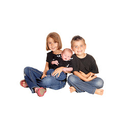 Image showing Sister and brother holding new baby.