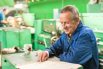 Image showing Elderly smiling worker looks in drawing