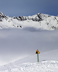 Image showing Warning sing on ski slope and mountains in fog