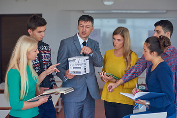 Image showing group of students working with teacher on  house model