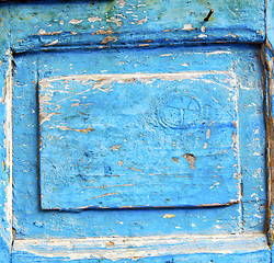 Image showing stripped paint in the blue wood door and rusty nail