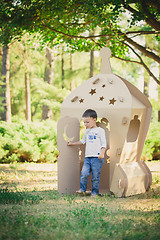 Image showing child playing in a cardboard spaceship. Eco concept