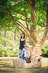 Image showing Mom and child playing in a cardboard boat. Summer day.